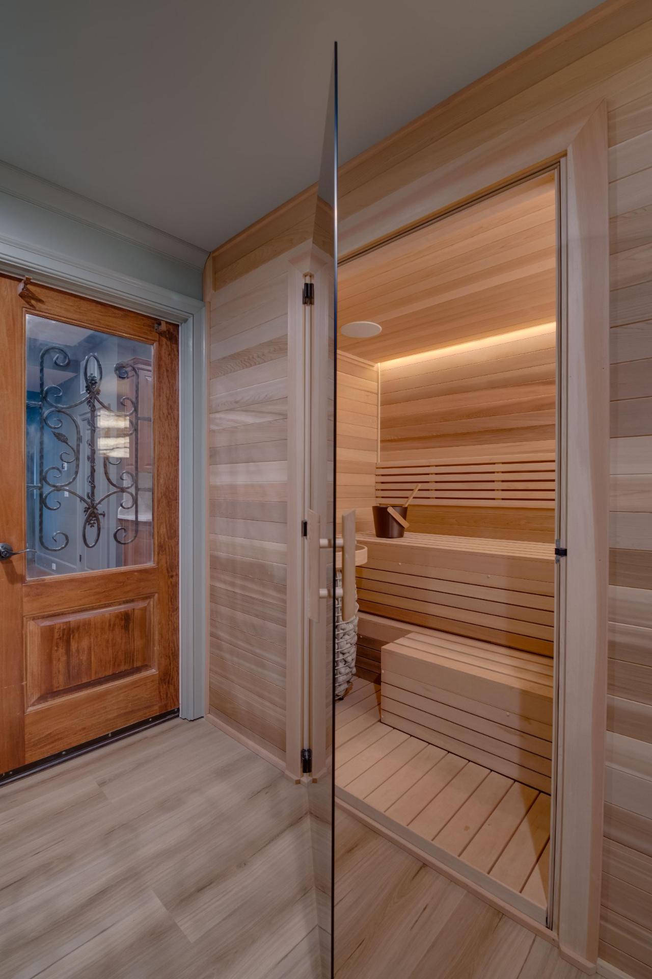 Custom indoor sauna entry — glass door opening into light hemlock interior