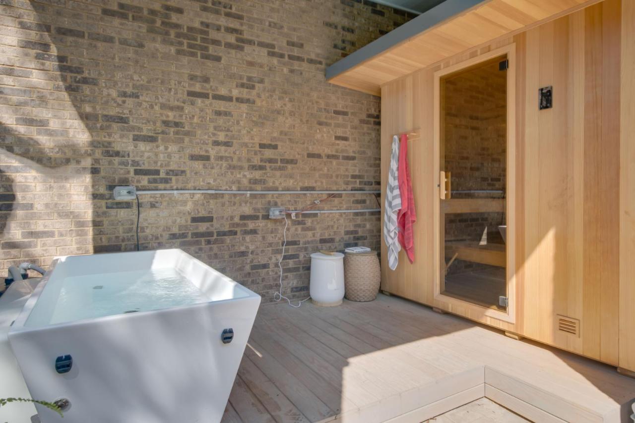 Custom outdoor cedar sauna paired with cold plunge tub on a covered patio