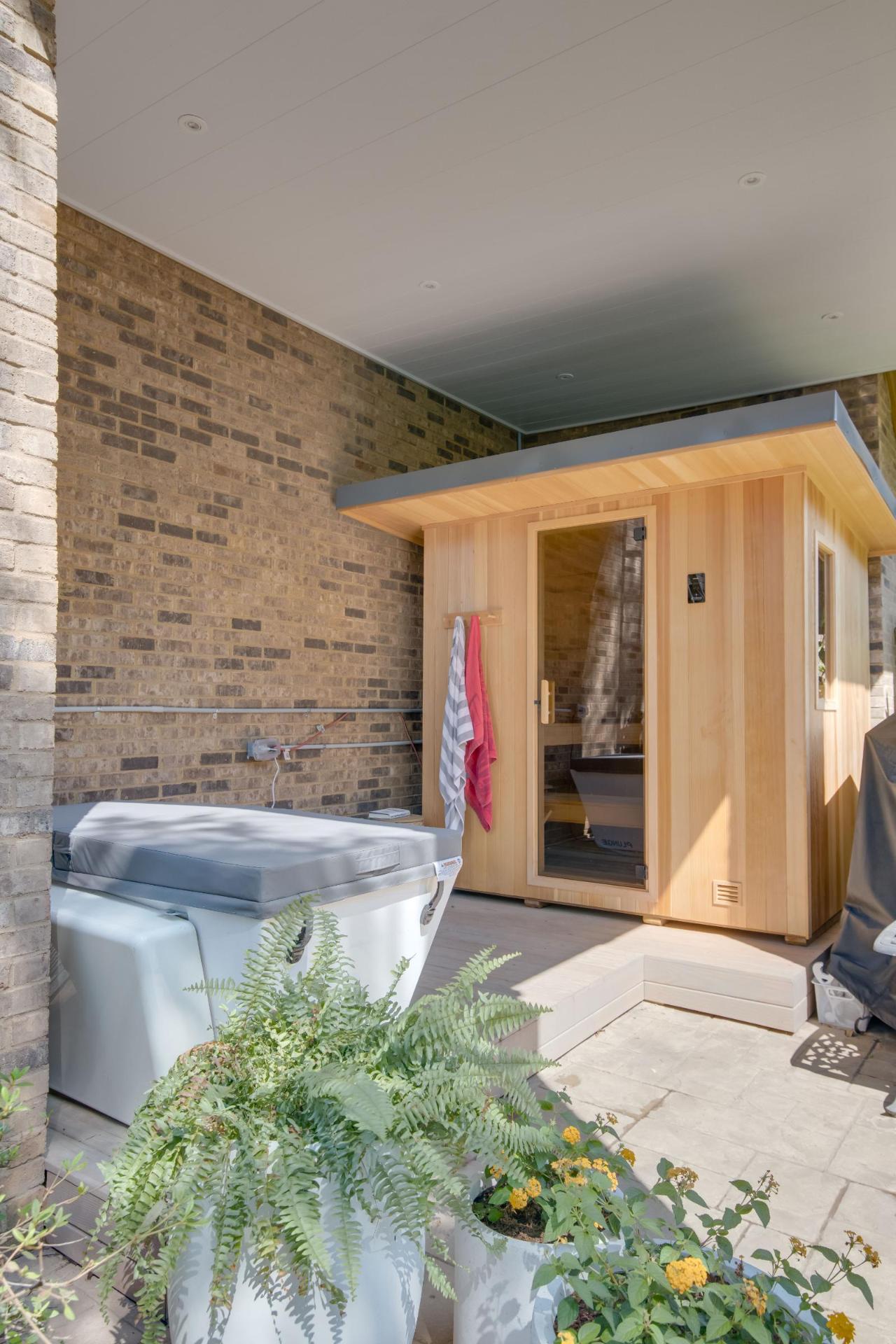 Cedar sauna cabin paired with hot tub on covered patio